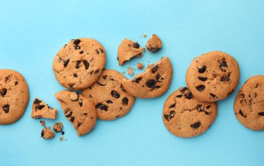 Açık mavi arka planda bir sürü çikolata parçacıklı kurabiye, düz uzanmış.