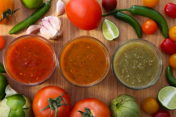 stock image Tasty salsa sauces and ingredients on wooden table, flat lay
