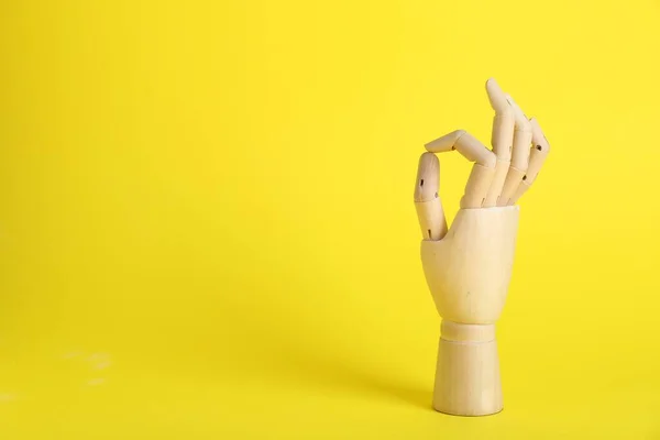 木制人体模特的手在黄色背景上表现出不错的姿势 案文的篇幅 — 图库照片