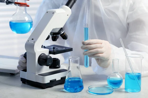 Scienziato Con Provetta Liquido Azzurro Vicino Microscopio Laboratorio Primo Piano — Foto Stock