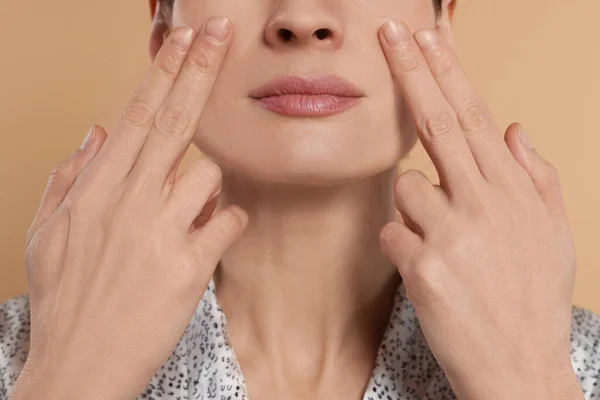 Wanita Memijat Wajahnya Latar Beige Closeup — Stok Foto