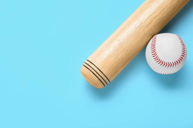 Wooden baseball bat and ball on light blue background, flat lay. Space for text