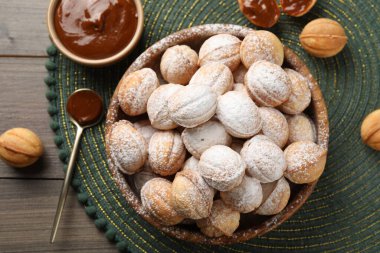 Bowl of delicious nut shaped cookies on wooden table, flat lay