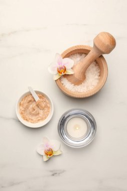 Flat lay composition with different spa products and flowers on white marble table