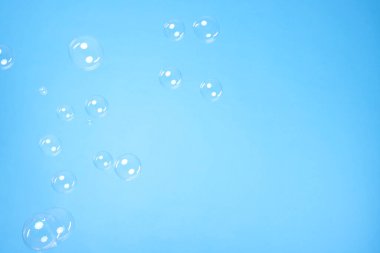 Many beautiful soap bubbles on light blue background. Space for text