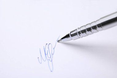 Signing on sheet of white paper with pen, closeup