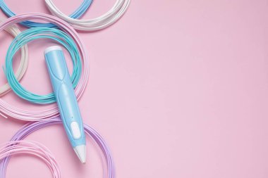 3D kalem ve pembe arka planda renkli plastik filamanlar, düz yatış. Metin için boşluk