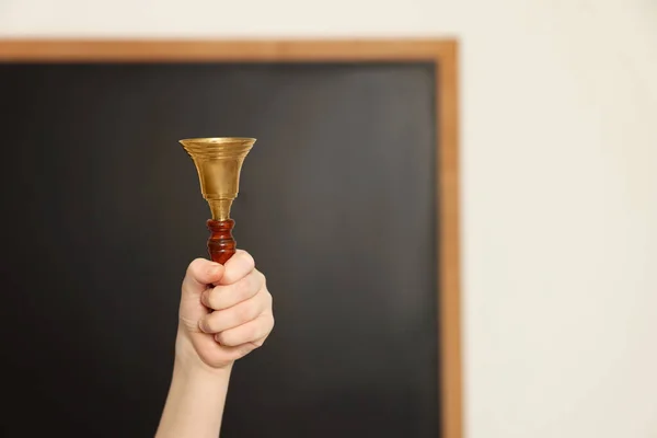 Boy ringing school bell in classroom, closeup. Space for text