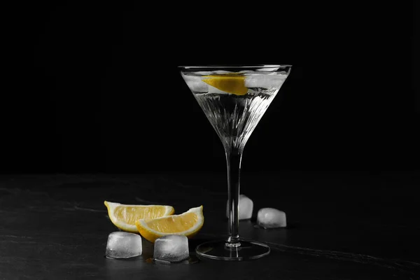黒の質感のテーブルの上にレモンと氷のキューブとさわやかなカクテルのマルティーニグラス — ストック写真