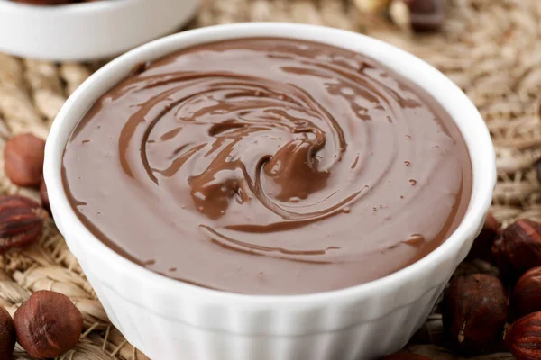 用美味的巧克力糊和坚果在柳条垫子上的碗 特写镜头 — 图库照片