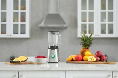 Mutfaktaki beyaz mermer tezgahta blender ve smoothie malzemeleri var.