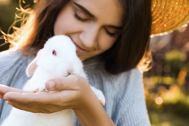 Happy woman with cute rabbit outdoors on sunny day, closeup