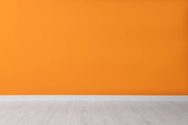 Turuncu duvarlı ve ahşap zeminli boş oda