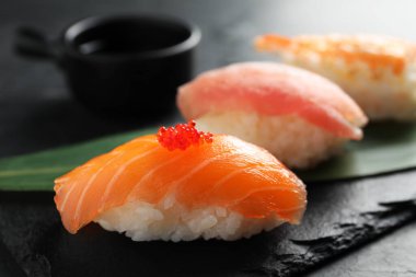 Serving board with delicious nigiri sushi and soy sauce on black table, closeup