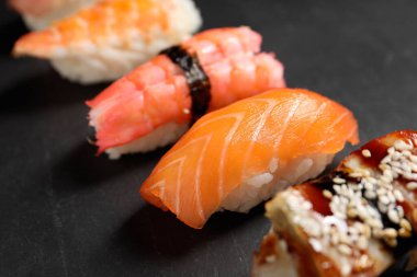 Delicious nigiri sushi on black table, closeup. Traditional Japanese cuisine