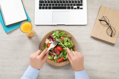 Ofis çalışanı iş yerinde öğle yemeği yiyor.