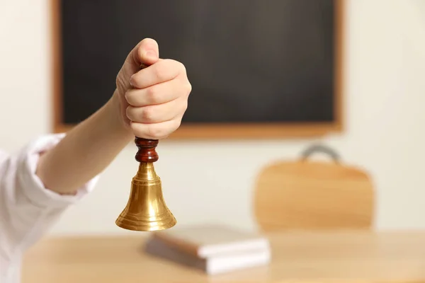 Boy ringing school bell in classroom, closeup. Space for text