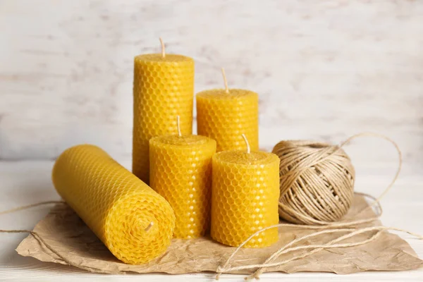 Stylish elegant beeswax candles and twine on white wooden table