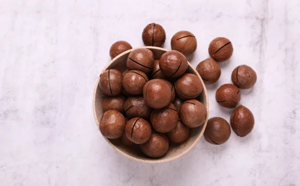 stock image Delicious organic Macadamia nuts on light gray table, flat lay