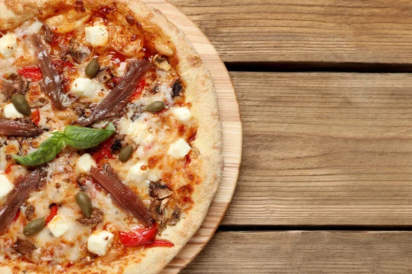 stock image Tasty pizza with anchovies, basil and olives on wooden table, top view. Space for text