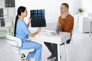 Doctor with neck MRI image consulting patient in clinic