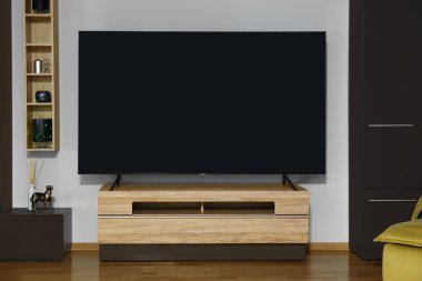 Ahşap masada modern plazma TV ve oturma odasındaki diğer mobilyalar.