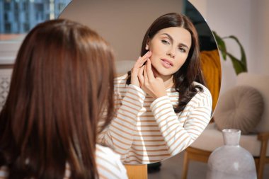 Genç bir kadın aynaya bakıyor ve içeride sivilce sıkıyor. Hormonal bozukluklar