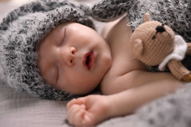 Yeni doğmuş şirin bebek yatakta diş çıkarma oyuncağıyla uyuyor, yakın plan.