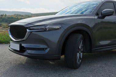 Black modern car parked on asphalt road, closeup