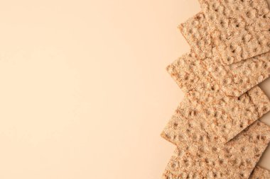 Fresh crunchy crispbreads on beige background, flat lay. Space for text
