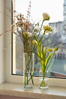 Different beautiful spring flowers on windowsill indoors