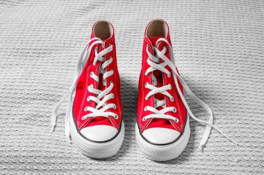 Açık gri kumaşta yeni bir çift şık kırmızı spor ayakkabı.