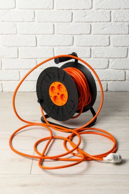 Uzatma kablosu beyaz tuğla duvarın yanında. Elektrikçi ekipmanı.