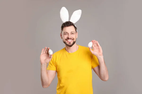 Glücklicher Mann Mit Hasenohren Stirnband Mit Bemalten Ostereiern Auf Grauem — Stockfoto