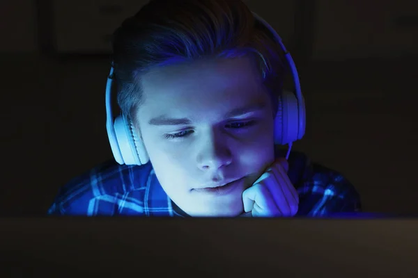 夜にコンピュータを使ってヘッドフォンで10代の少年 インターネット中毒 — ストック写真