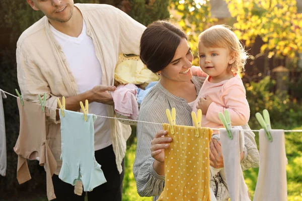 Glad Familie Hængende Baby Tøj Med Tøjspins Vaskelinjen Til Tørring - Stock-foto