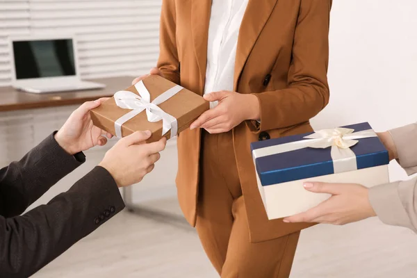 Colleague presenting gifts to man in office, closeup
