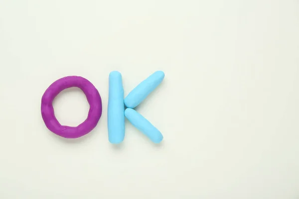 Stock image Word Ok made of colorful plasticine on white background, top view. Space for text