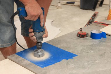 Worker making socket hole in tile indoors, closeup