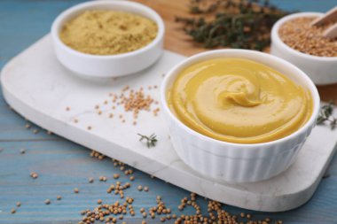 Lezzetli hardal ve tohumlar açık mavi ahşap masada, yakın plan.