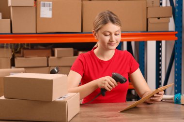 Post office worker with scanner reading parcel barcode at counter indoors