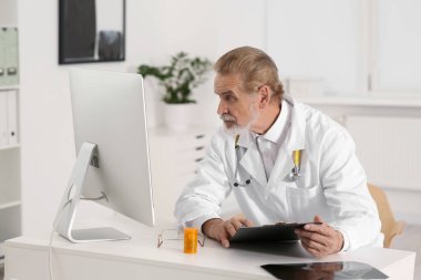 Doctor with patient's medical card at table in clinic