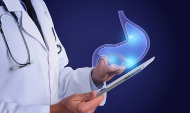 Mide ekşimesinin ve diğer gastrointestinal hastalıkların semptomları. Doktor mavi arka planda tablet kullanıyor, yakın plan. Mide illüstrasyonu aygıtın üzerinde
