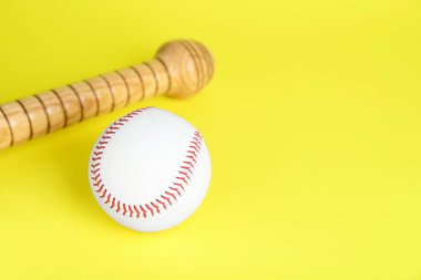 Tahta beyzbol sopası ve top sarı arka planda, mesaj için boşluk. Spor malzemeleri.