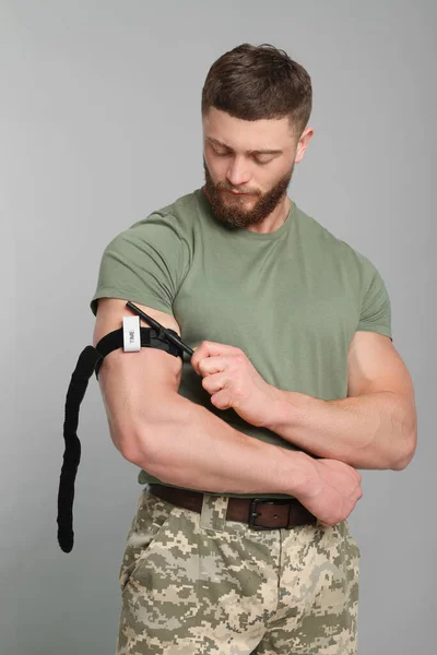 Soldaat Militair Uniform Met Medisch Tourniquet Arm Tegen Lichtgrijze Achtergrond — Stockfoto
