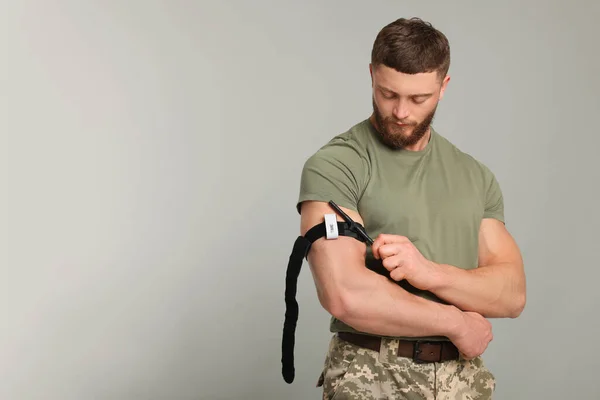 薄い灰色の背景に腕の上に医療用のトーナメントを適用する軍の制服の兵士 テキストのスペース — ストック写真