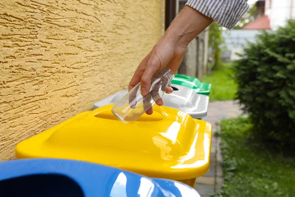 stock image Woman throwing glass bottle into recycling bin outdoors, closeup