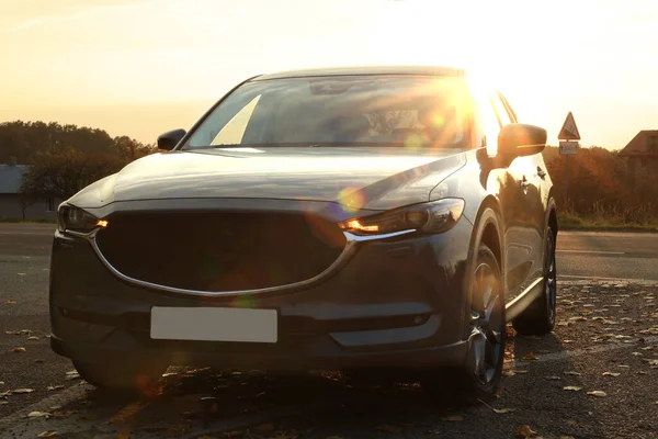 stock image Black modern car parked on road at sunset