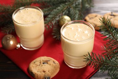 Lezzetli eggnog, kurabiyeler ve ahşap masada köknar dalları.