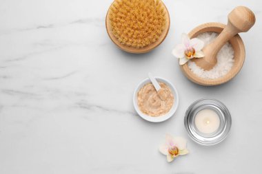 Flat lay composition with different spa products and flowers on white marble table. Space for text
